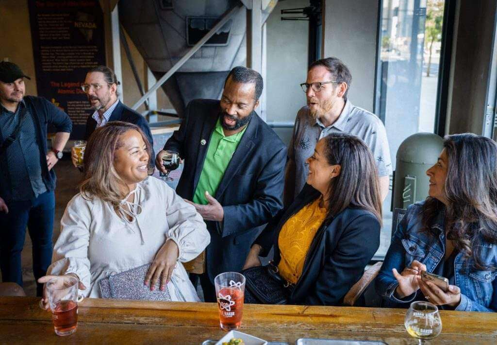 People talking and smiling around a table at a StartUpNV community gathering
