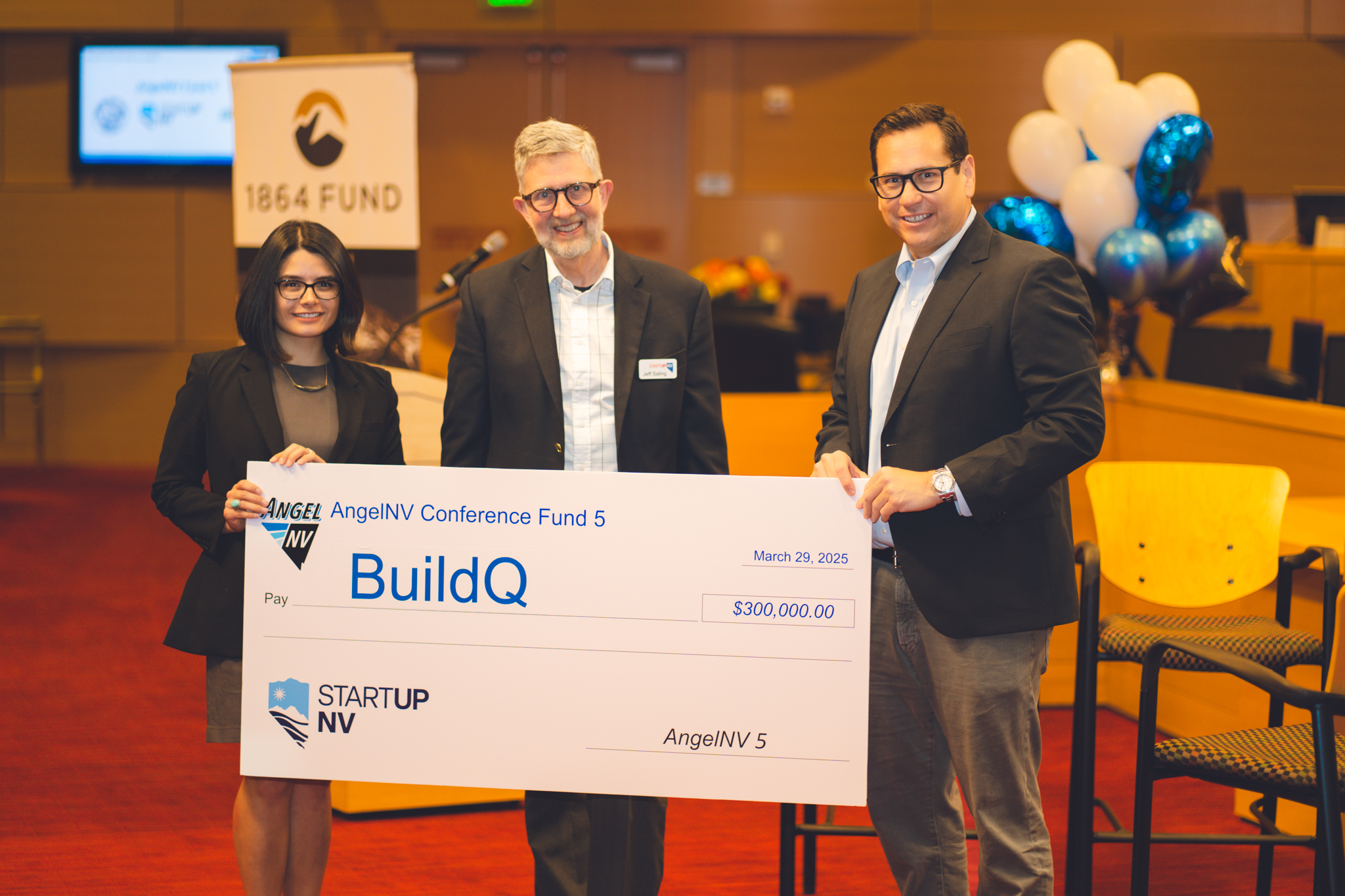 Three people holding a $300,000 AngelNV Conference Fund 5 check for BuildQ, dated March 29, 2025