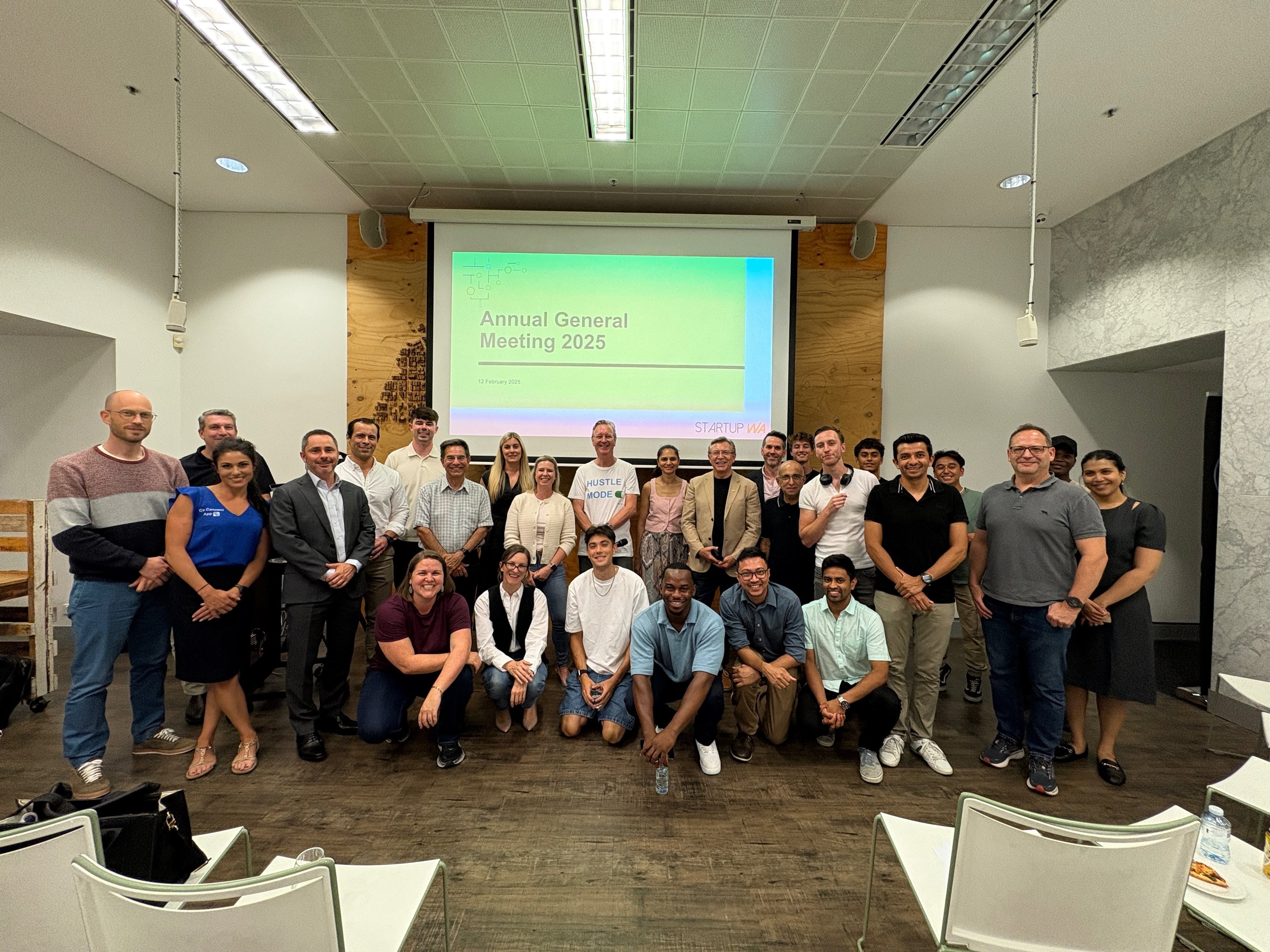StartupWA community members gathered beneath a 2025 annual general meeting slide