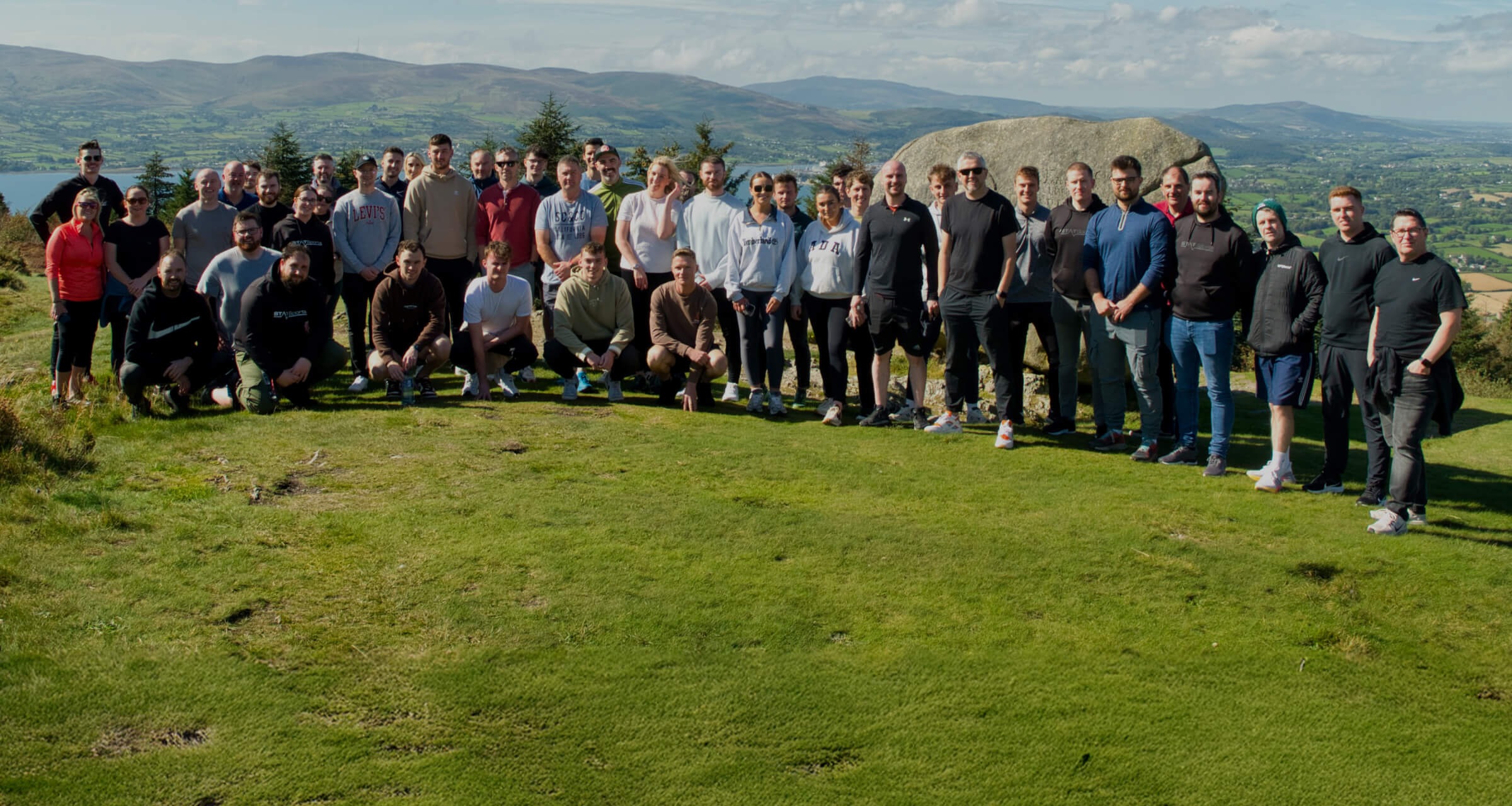 STATSports colleagues posing together outdoors with hills and water behind them