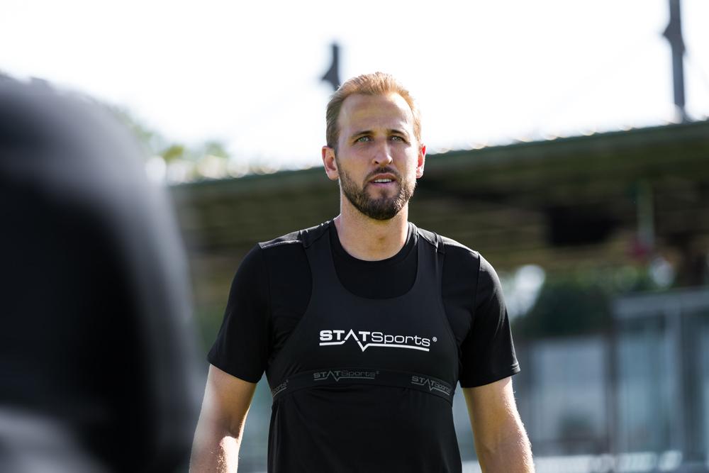 A football player wearing a black STATSports performance vest on a training ground