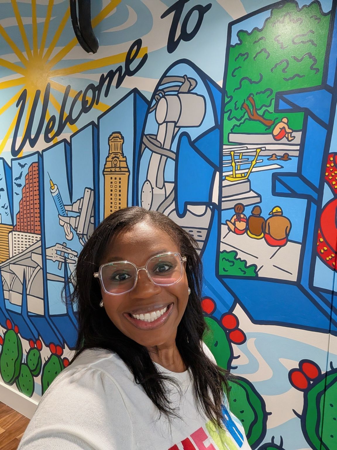 Stella Prefach smiling in front of a colorful Austin mural
