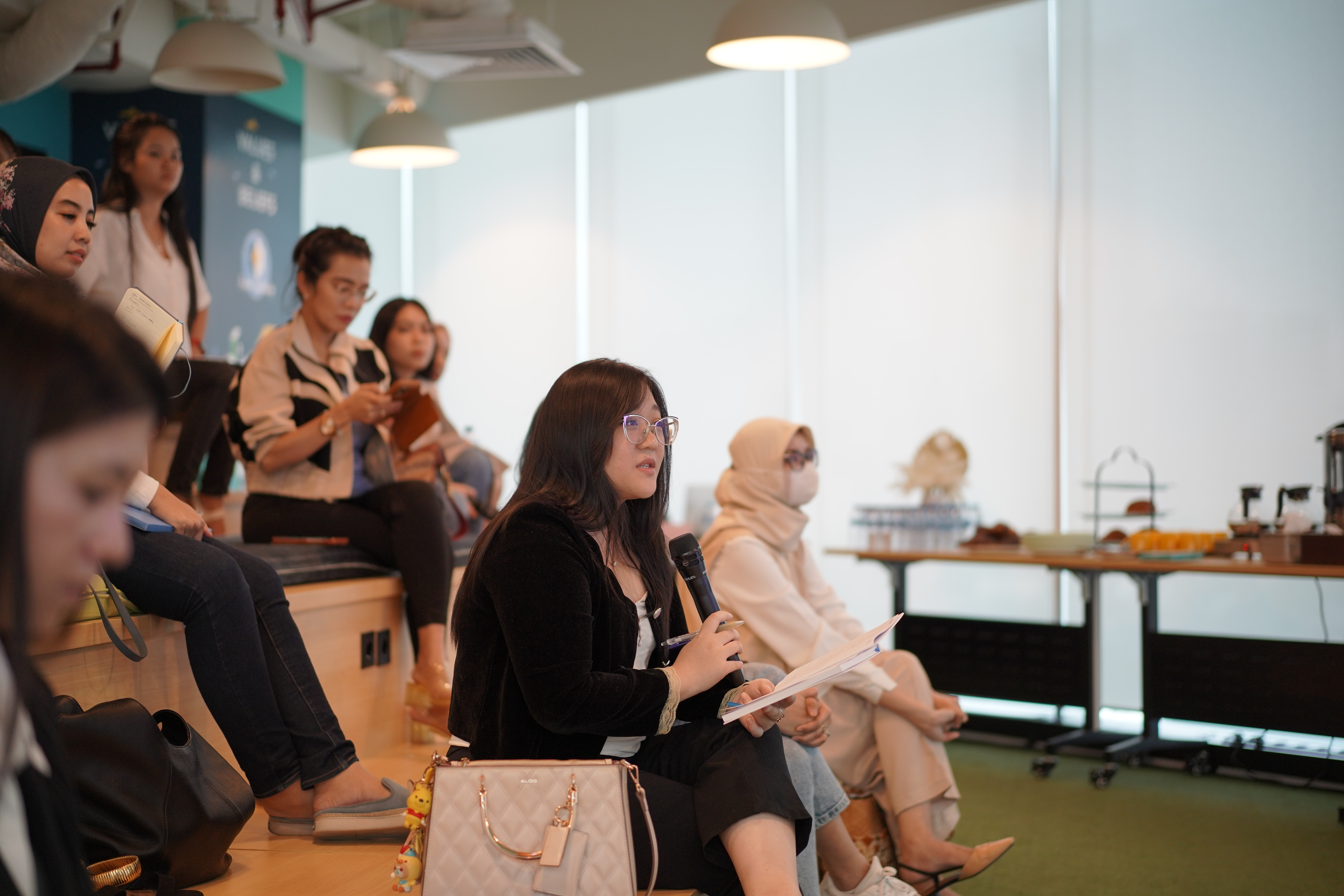 A participant holding a microphone and notes during a Stellar Women session