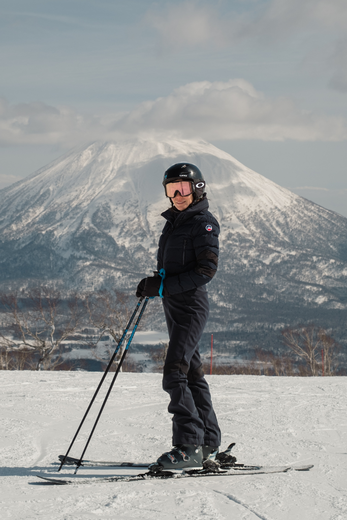 Stephanie Chai on skis in Hokkaido with a snow-covered mountain behind her