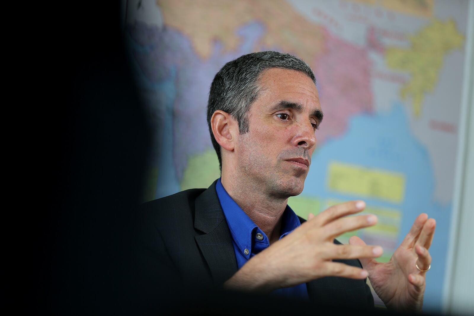 Stephen Fernands speaking with his hands raised in front of a map