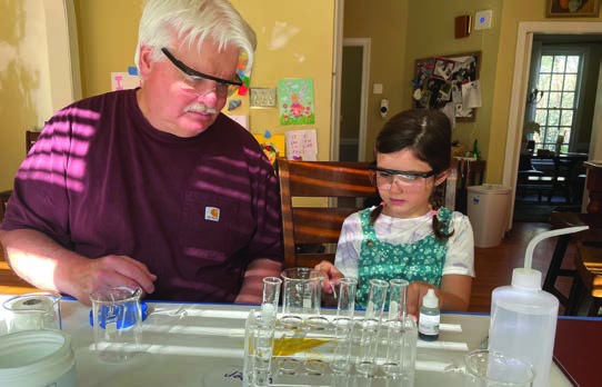 Stephen Fransen and his granddaughter Ruby wearing safety glasses while working on a chemistry experiment