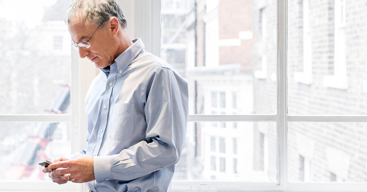 Stephen Kaufer looking at a phone beside a bright window