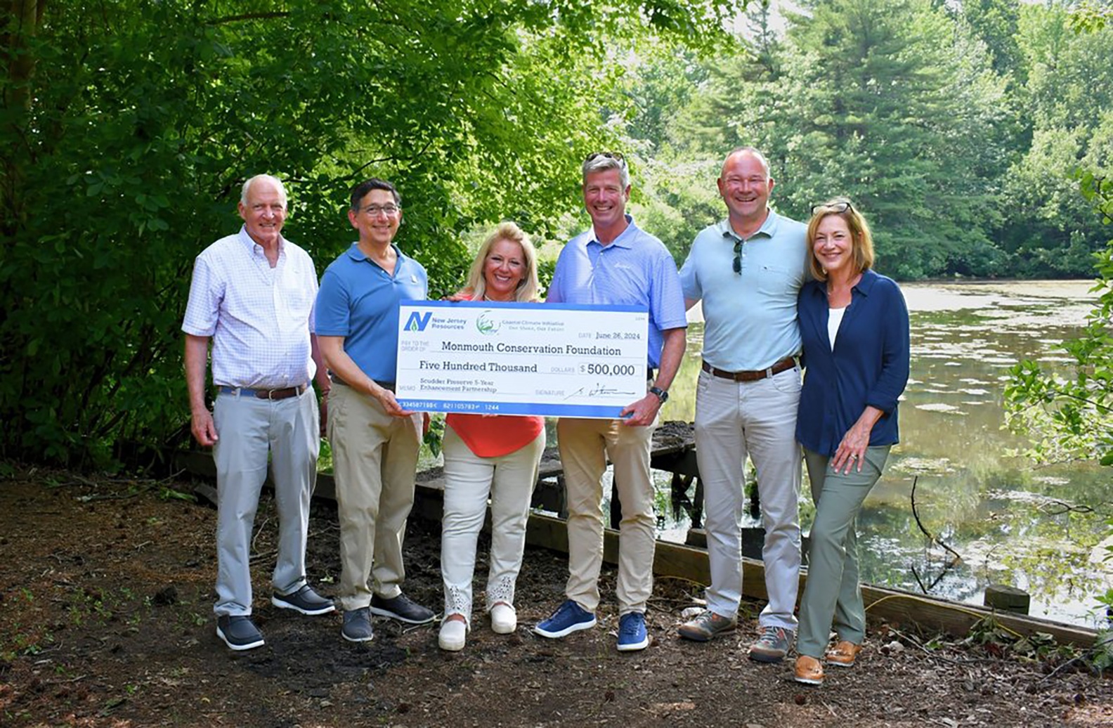 Stephen Westhoven, fourth from left, with NJR executives and Monmouth Conservation Foundation representatives holding a ceremonial $500,000 check at Scudder Preserve