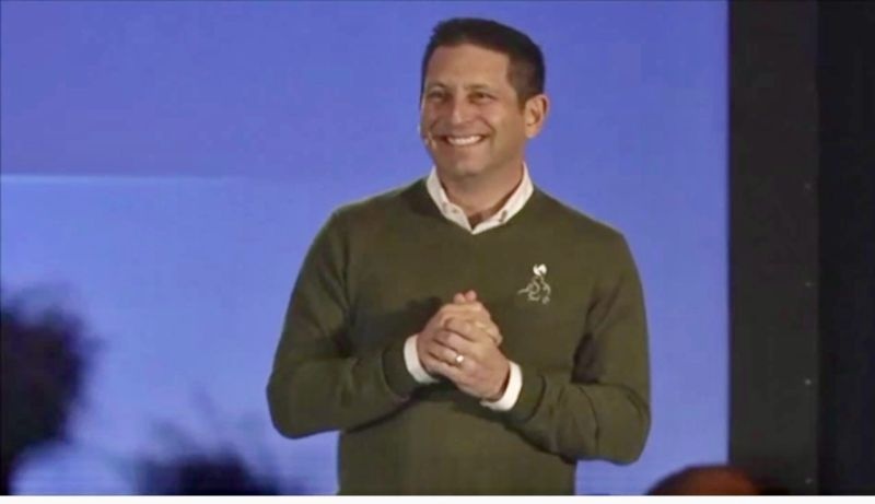 Steve Bilt smiling onstage at his first team meeting after returning to Smile Brands