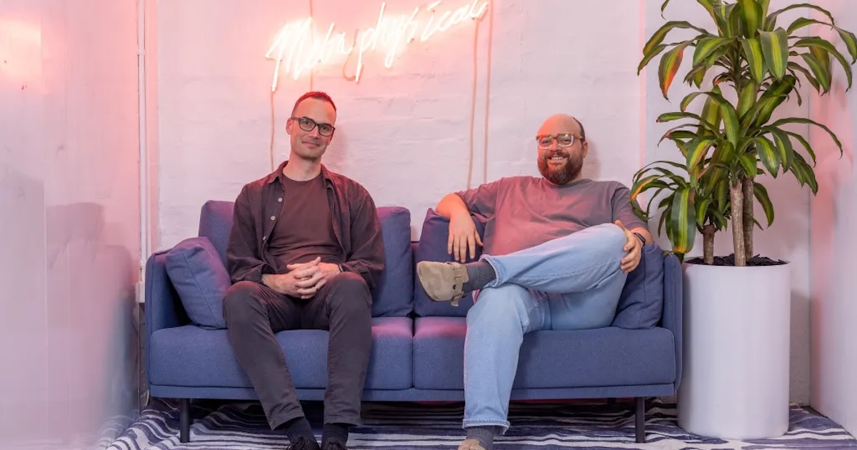 Jamie Hall, left, and Steve Hind sitting on a blue sofa in an office
