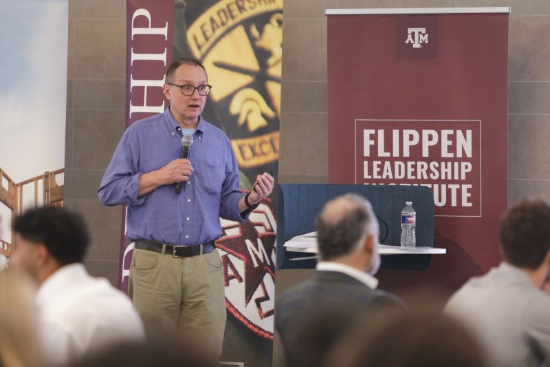 Steve Lawrence speaking into a microphone to students at the Flippen Leadership Institute at Texas A&M
