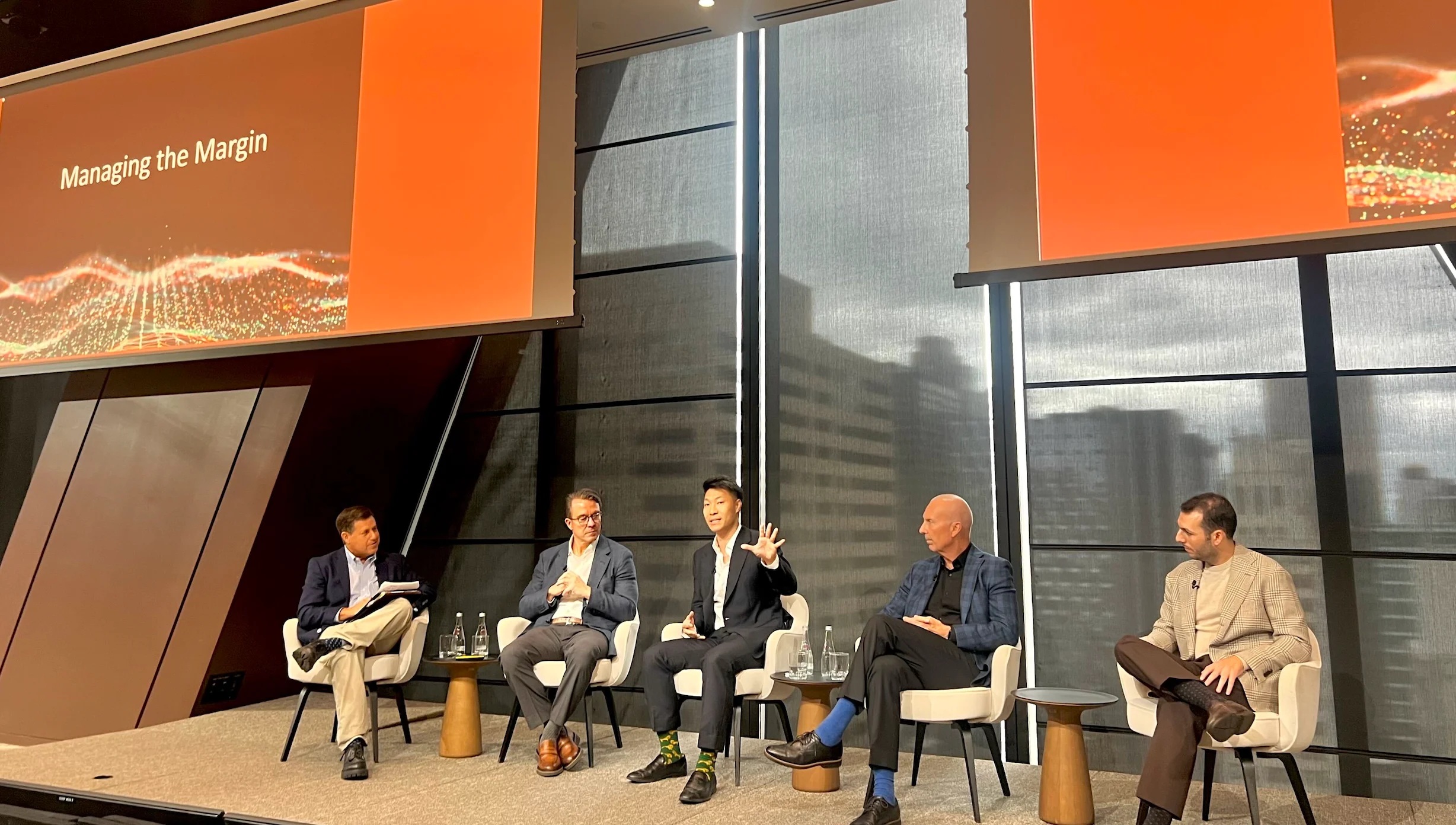Steve Liou, seated in the center, speaks on a five-person panel beneath a Managing the Margin presentation.