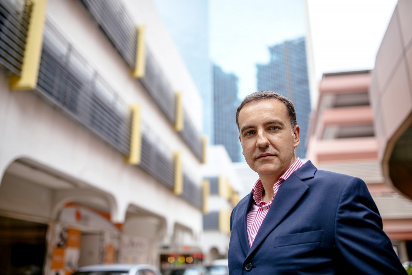 Steve Melhuish outside among Singapore buildings, wearing a navy jacket and striped shirt