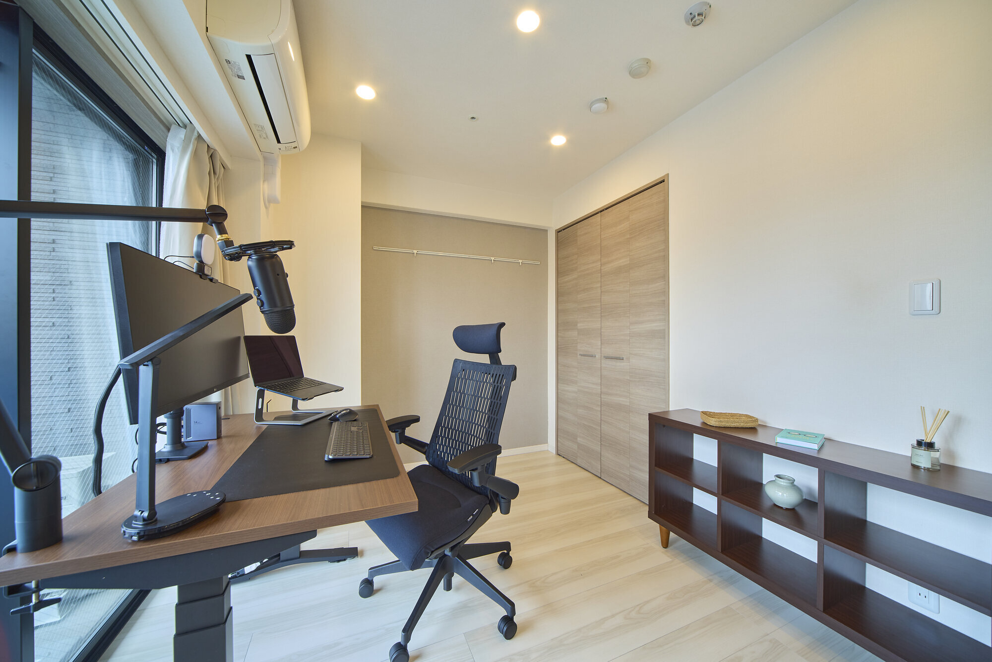 An Anyplace Tokyo apartment workspace with ultrawide monitor, microphone, adjustable desk, and ergonomic chair