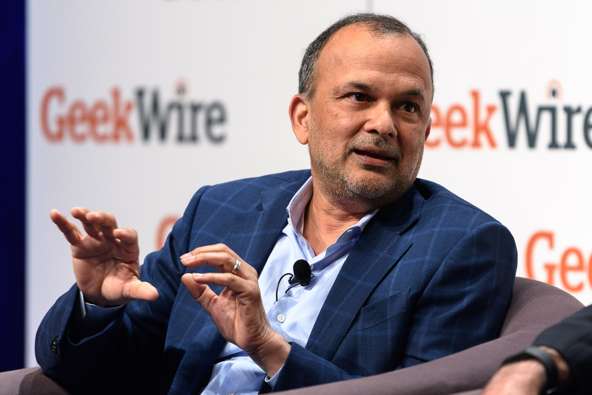 Steve Singh gestures while seated onstage at the 2017 GeekWire Cloud Tech Summit