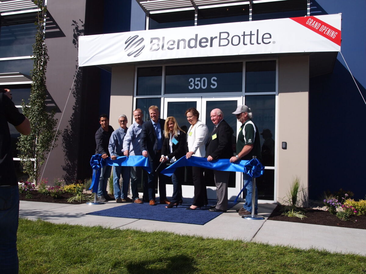 Kim Sorensen cuts a blue ribbon with Steve Sorensen beside her at BlenderBottle’s second Lehi building in September 2017.