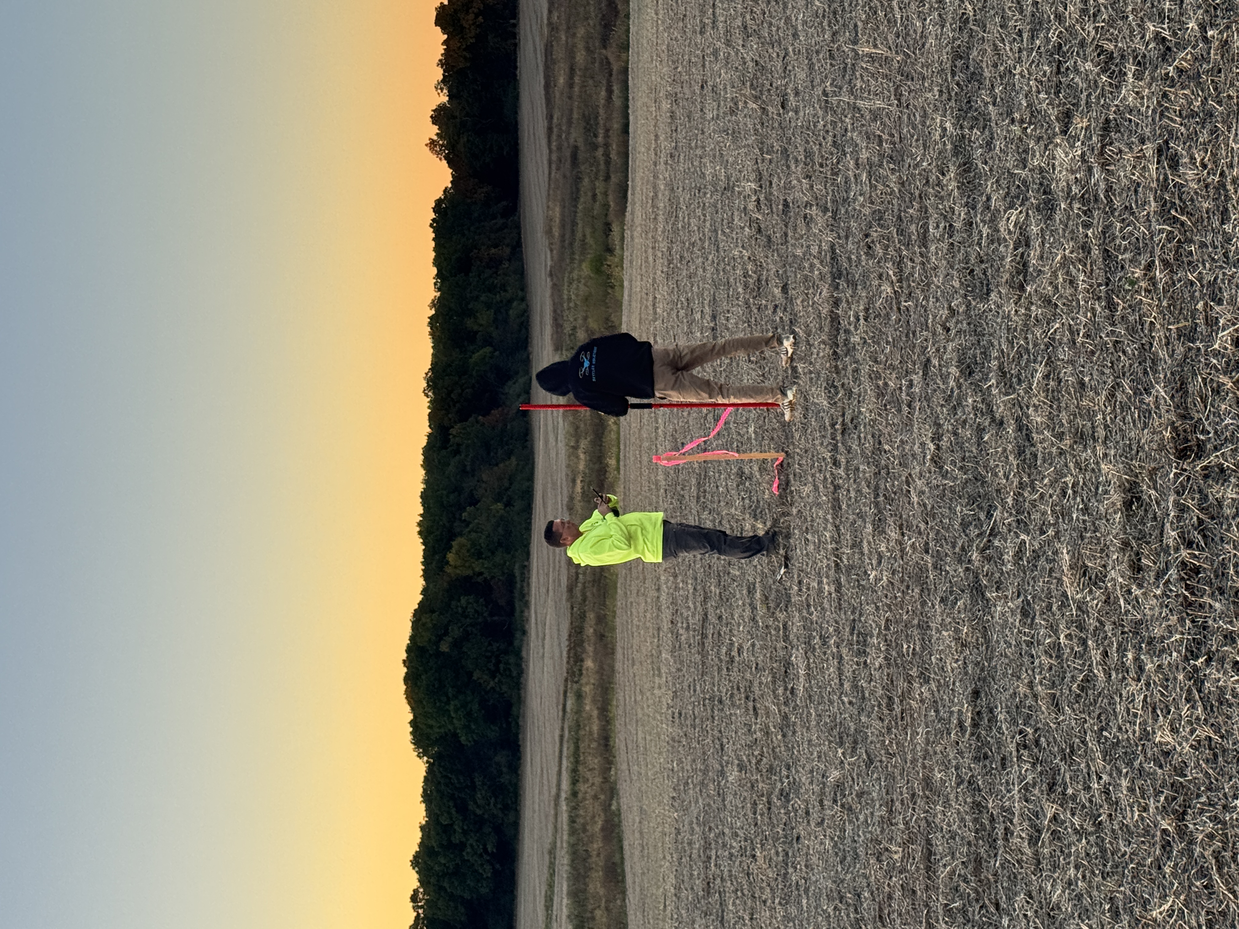 Survey workers checking field equipment in an open field at dusk