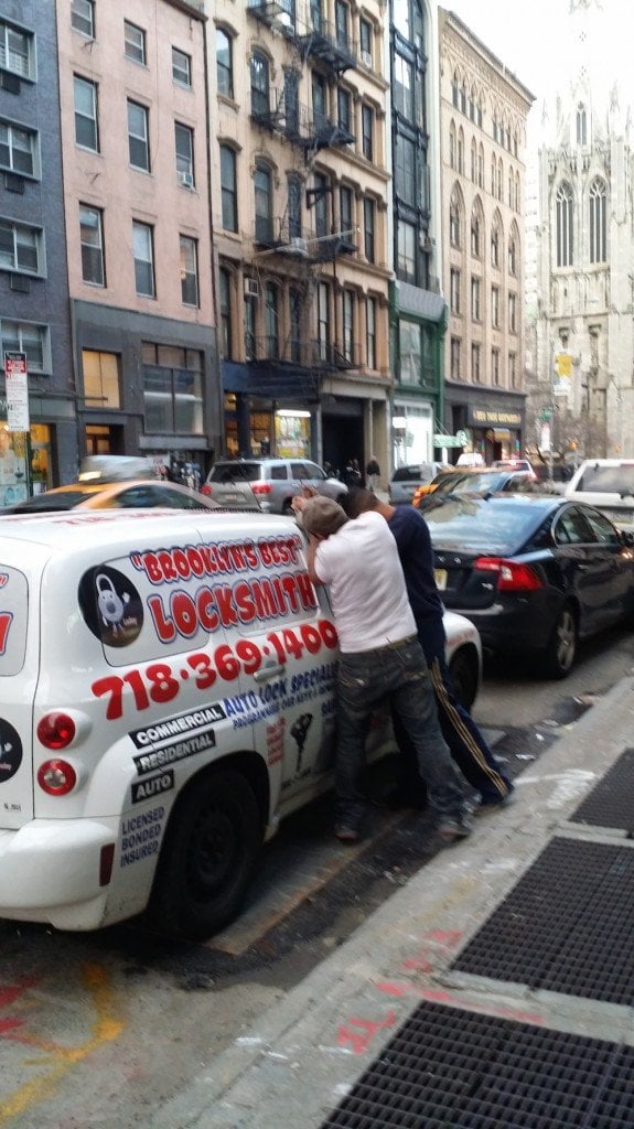 Two people looking through the window of a locksmith’s van parked on a city street