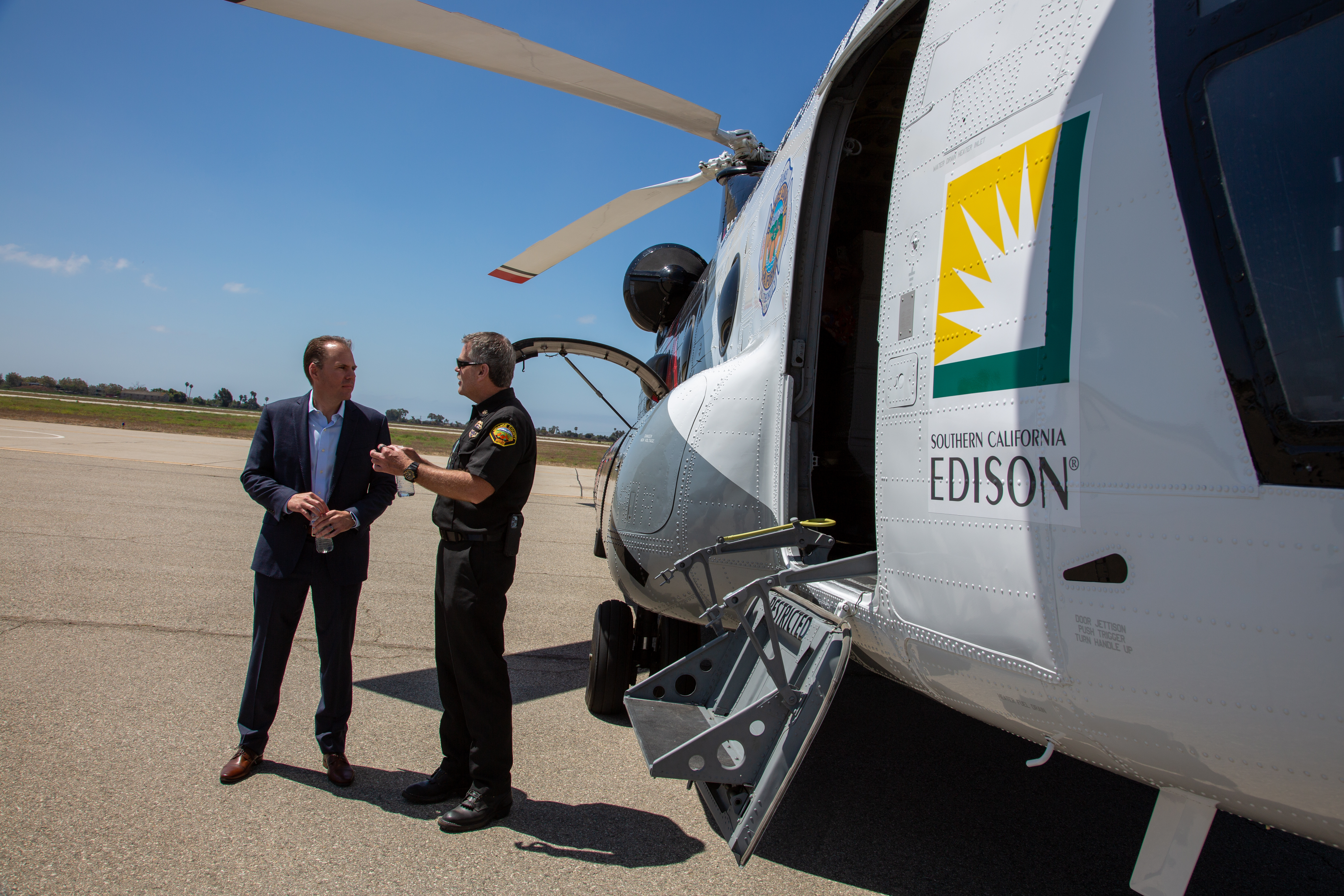 Powell, left, speaks with Orange County Fire Authority Chief Brian Fennessy beside a firefighting helitanker.