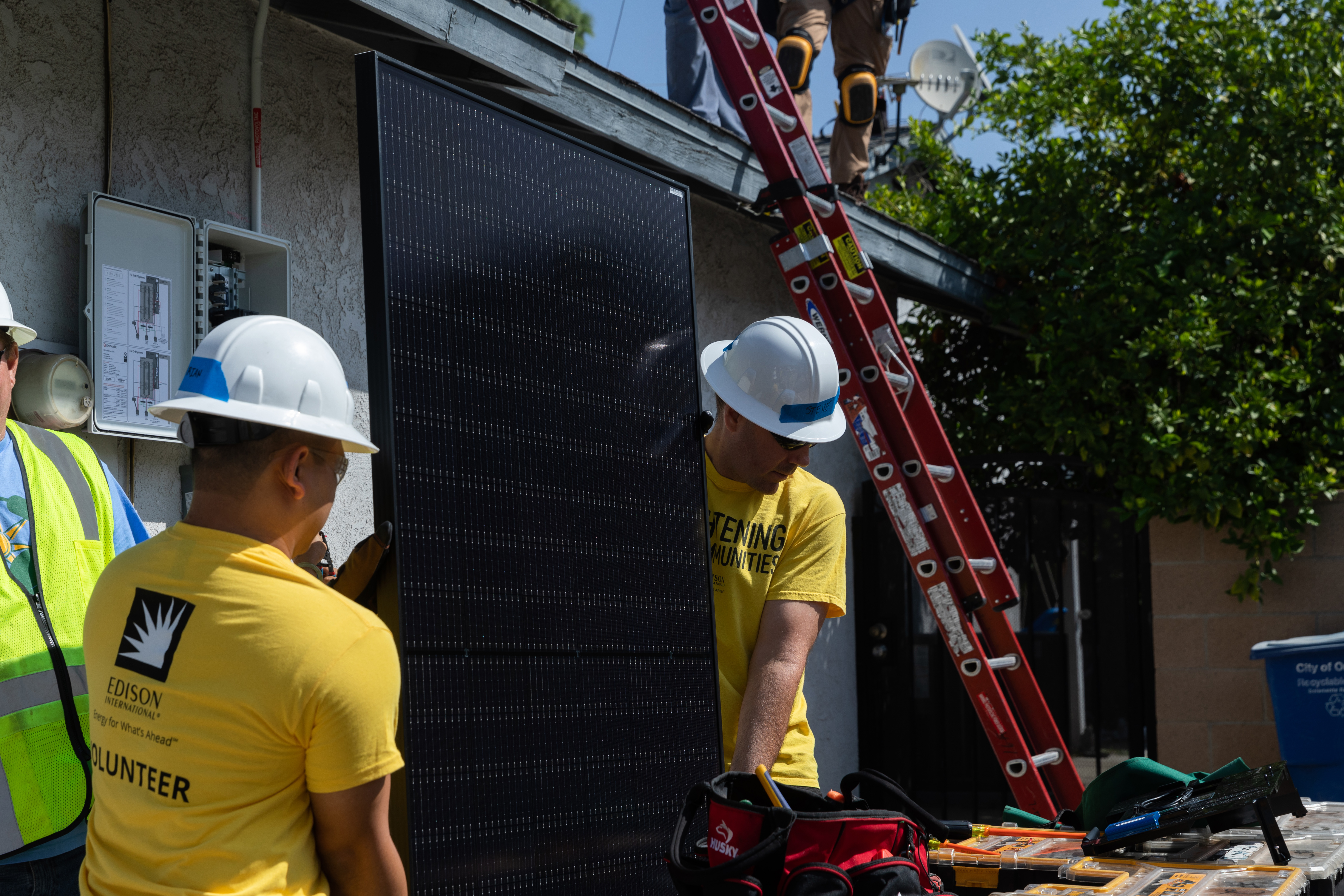 Steve Powell, right, and Brian Mauleon carry a solar panel during a volunteer installation in Ontario.