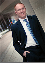 An older photograph of Steven R. Jolly standing outdoors in a suit and patterned tie