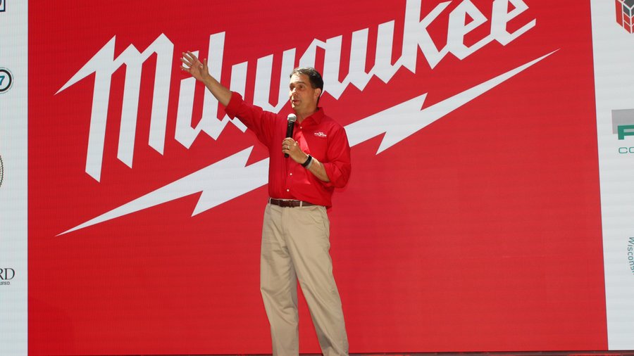 Steve Richman in a red Milwaukee shirt speaking into a microphone at the 2018 headquarters expansion groundbreaking