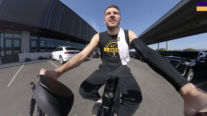 Luka Dončić on a bicycle with a speaker visible beside the handlebars