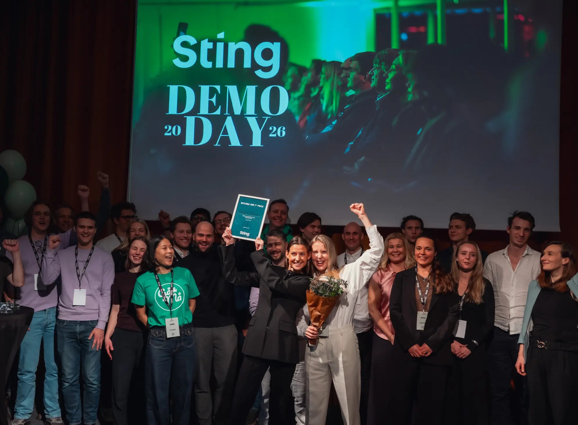 Two women from Sting’s 2025 cohort celebrating onstage at Demo Day 2026
