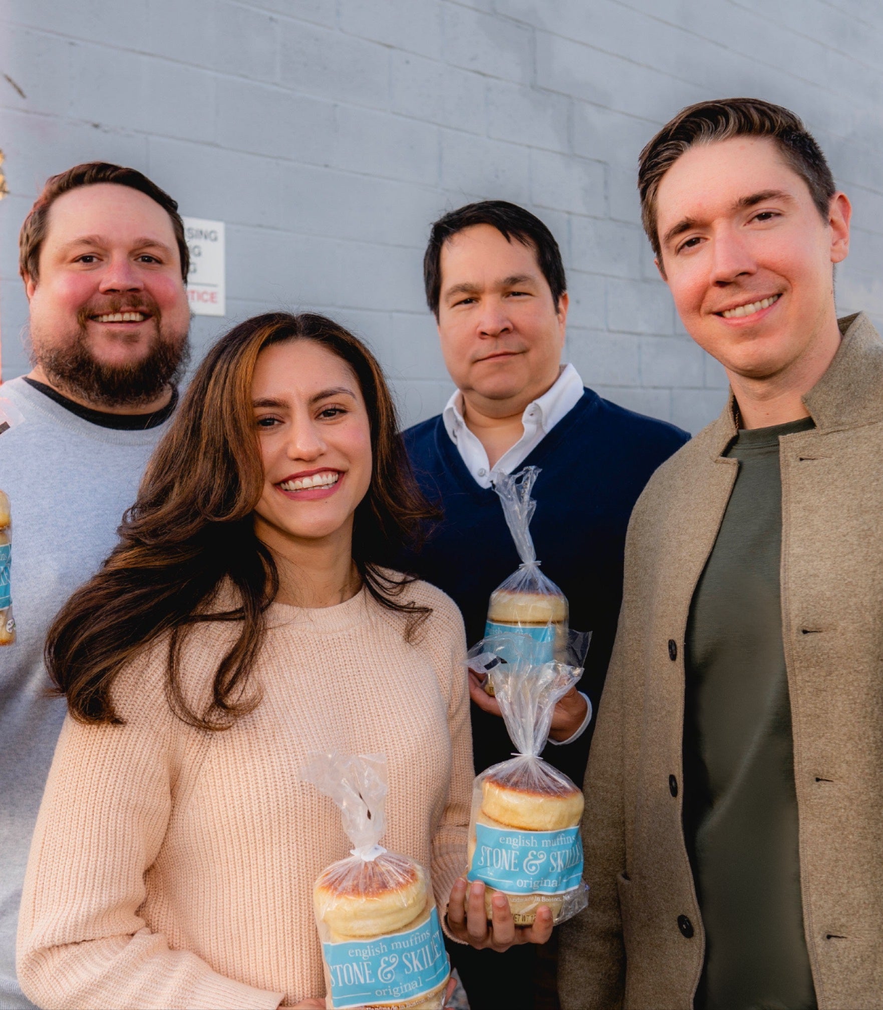 Four people pictured holding Stone & Skillet English muffin packages on the company website