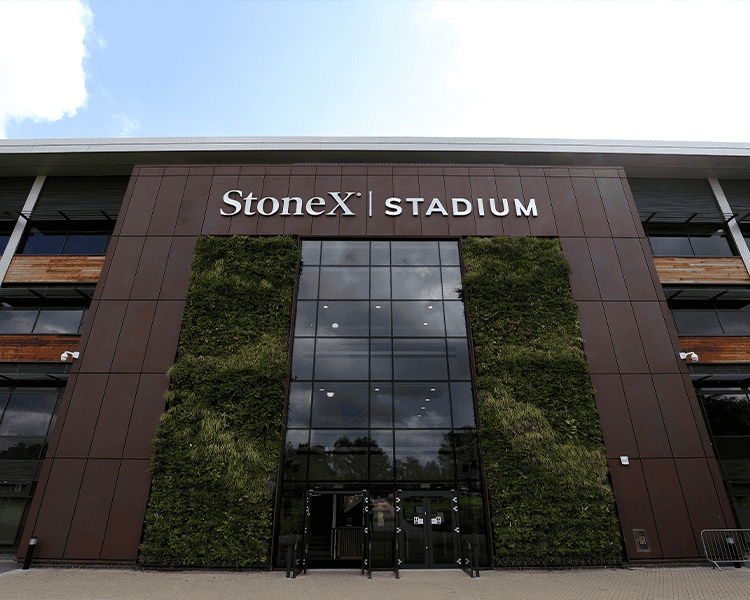 The entrance to StoneX Stadium, with its name above a glass facade and living walls