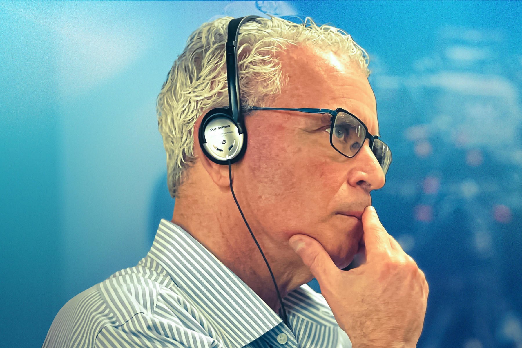 Eric Jaye wearing headphones, his hand resting against his chin