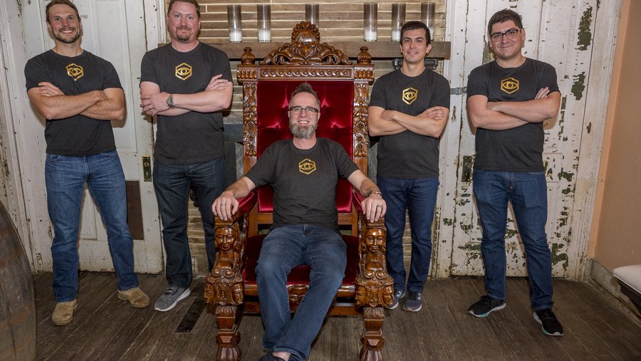 Launch-era Strangeworks team gathered around whurley seated in a wooden chair