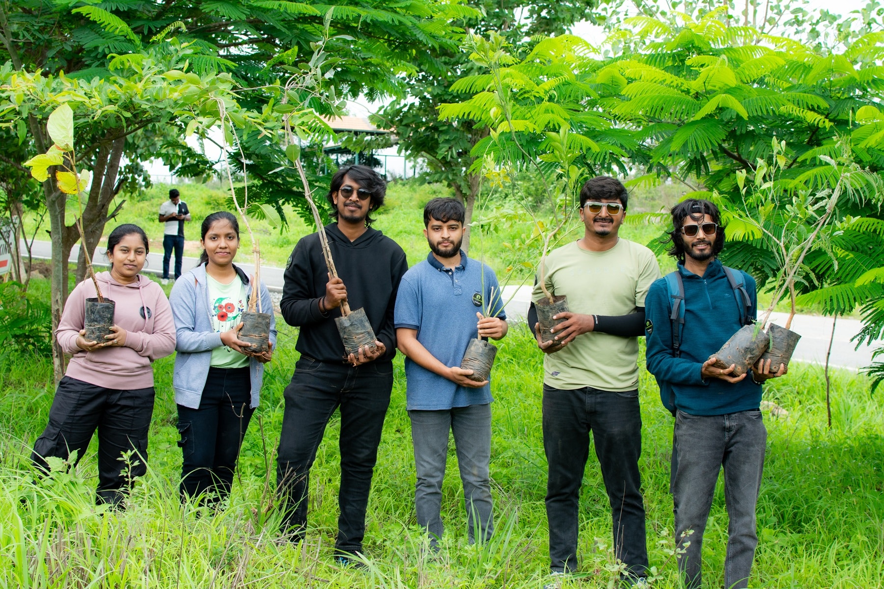 Stratogent team members outdoors holding saplings during a community tree-planting activity