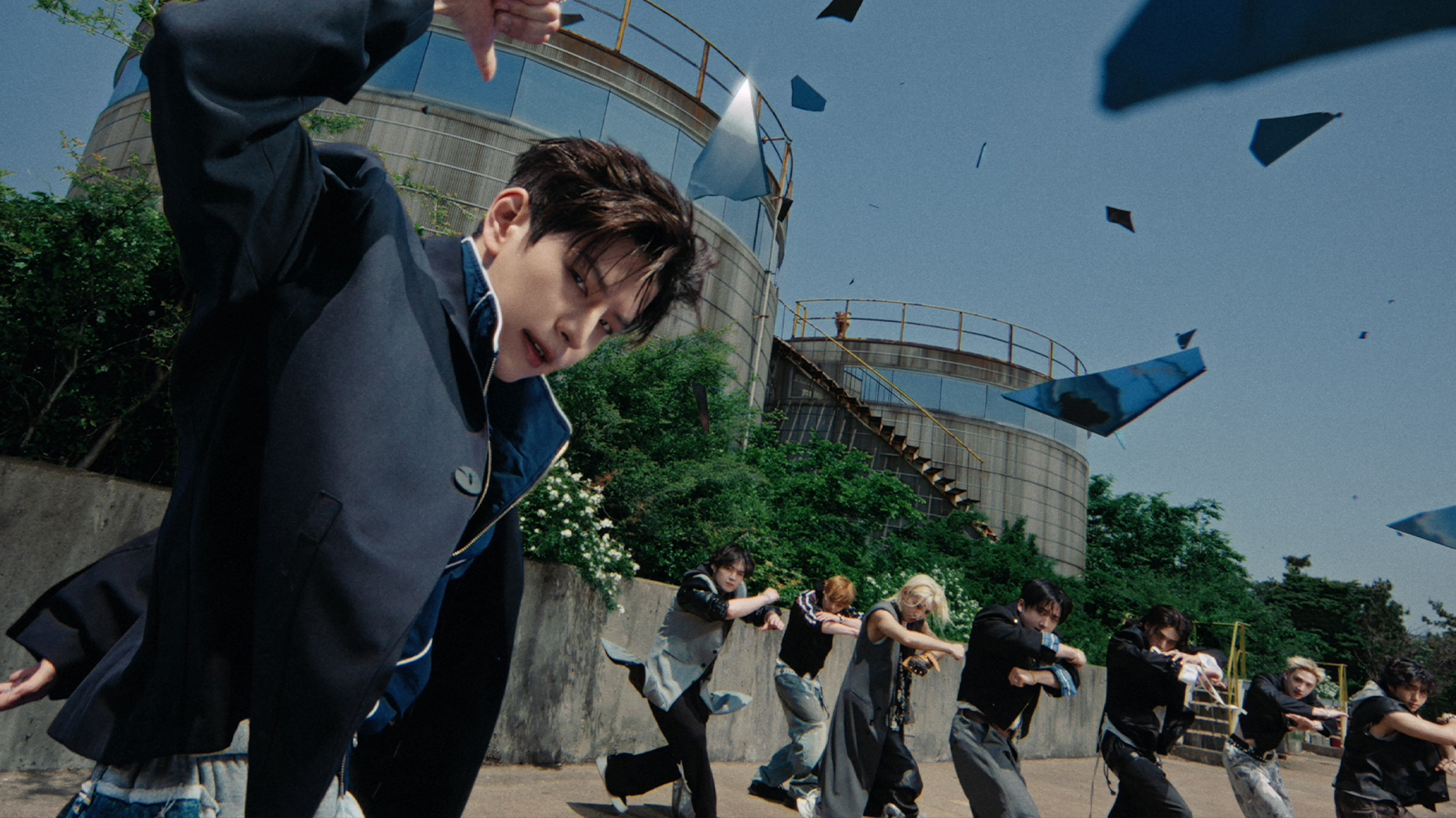 The eight members of Stray Kids performing a synchronized gesture outdoors