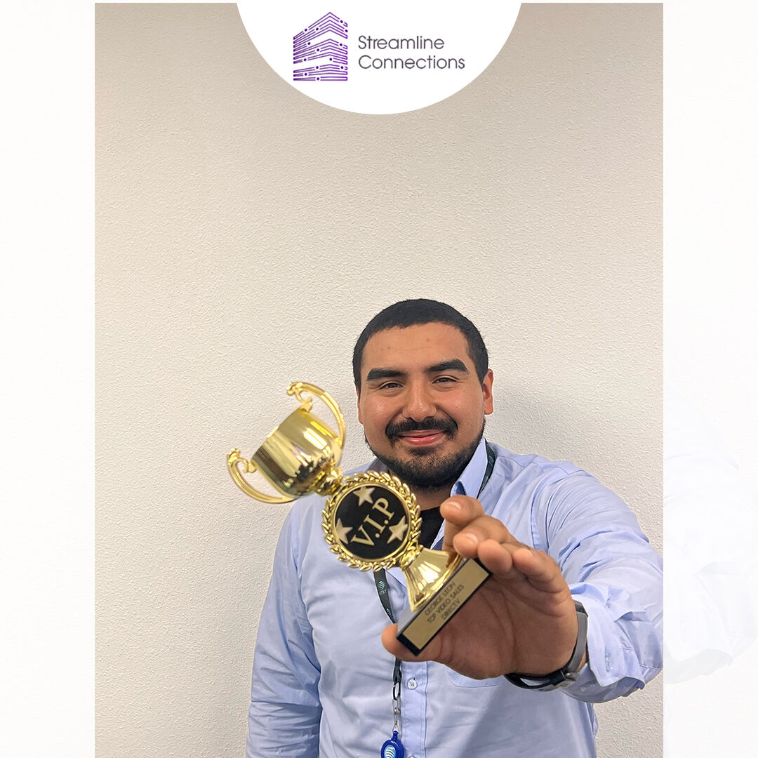 A Streamline Connections team member holding a gold sales trophy