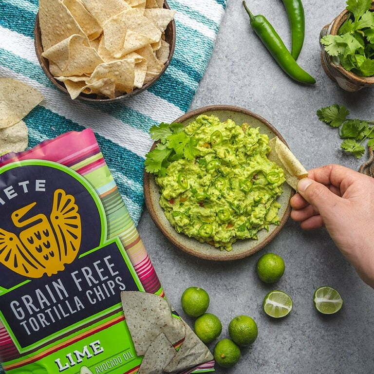 Siete grain-free tortilla chips beside guacamole, limes, and peppers