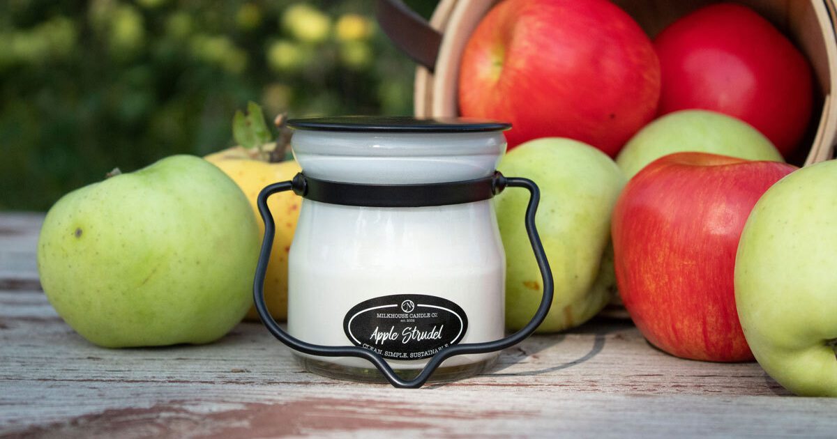 A Milkhouse Candle Co. apple strudel candle surrounded by apples