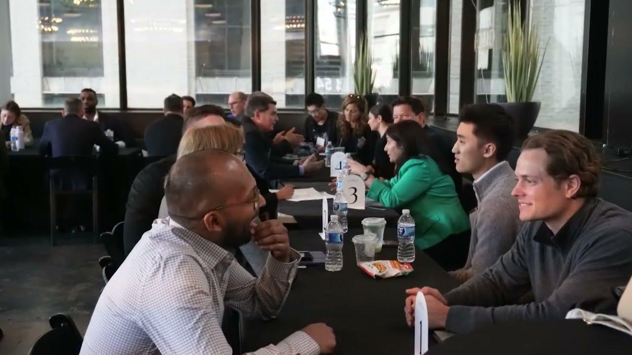 Attendees seated across narrow tables in the StrtupBoost HealthTech Investor Summit video