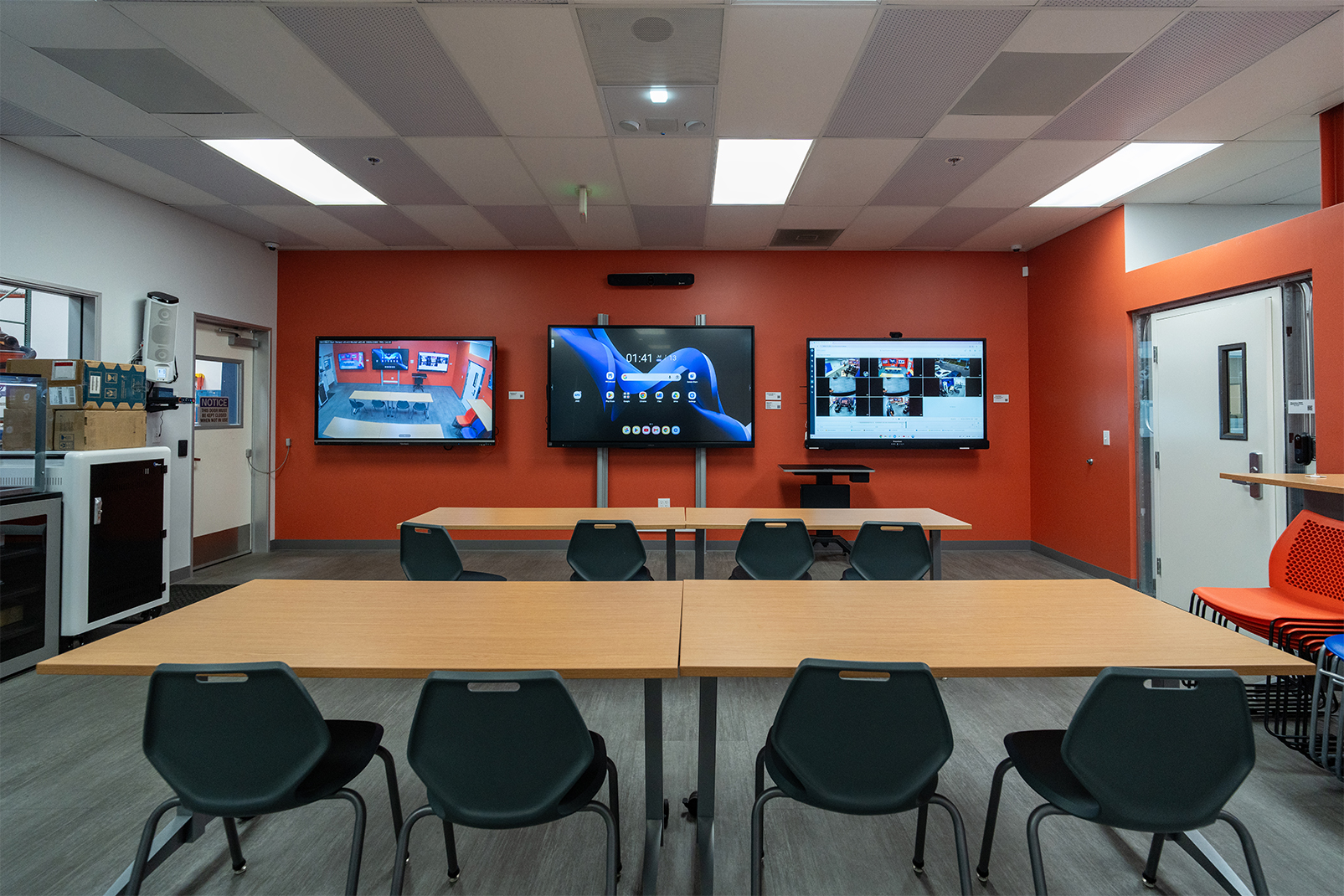 STS customer experience center with tables, teal chairs, and wall-mounted displays
