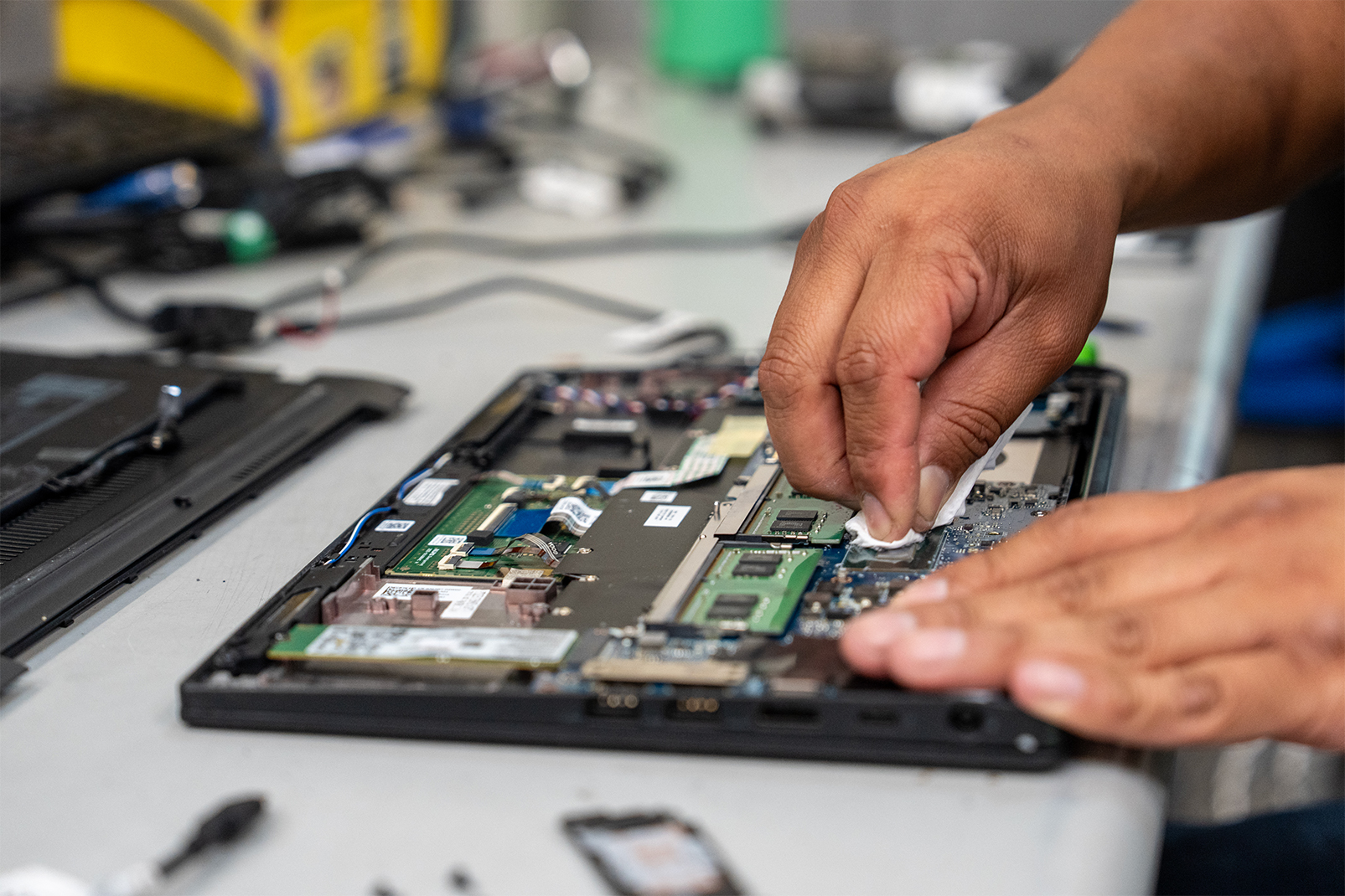 A technician working on the exposed internal components of a laptop at a repair bench