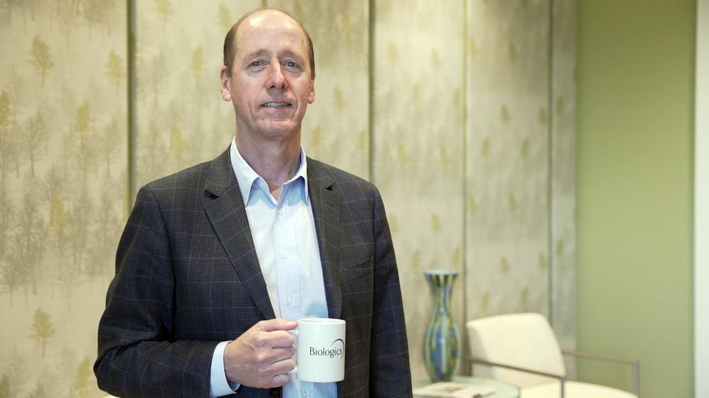 Stuart Frantz standing in an office holding a company mug