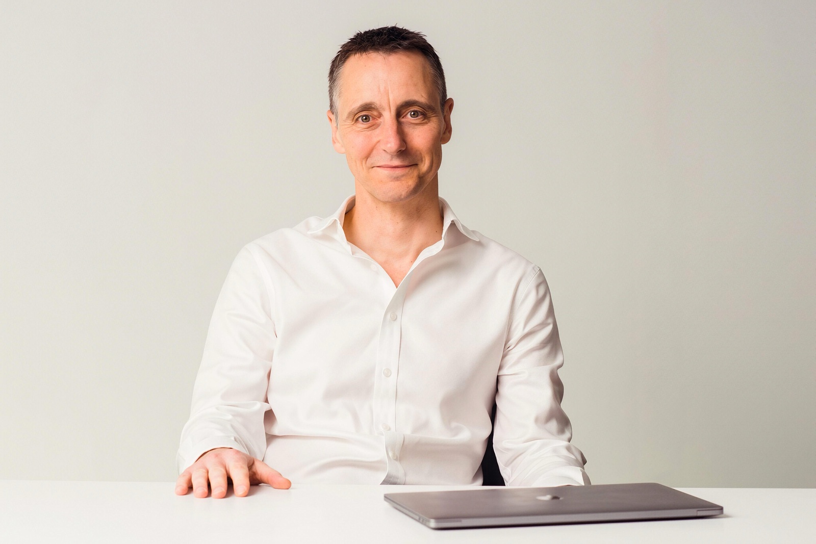 Stuart Green seated at a table with a closed laptop