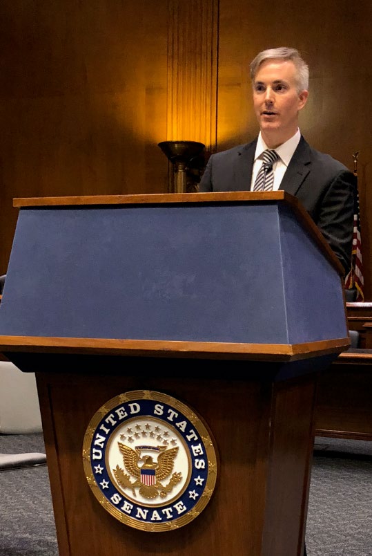 Stuart Jones speaking behind a United States Senate podium at the 2019 Parliamentary Intelligence-Security Forum
