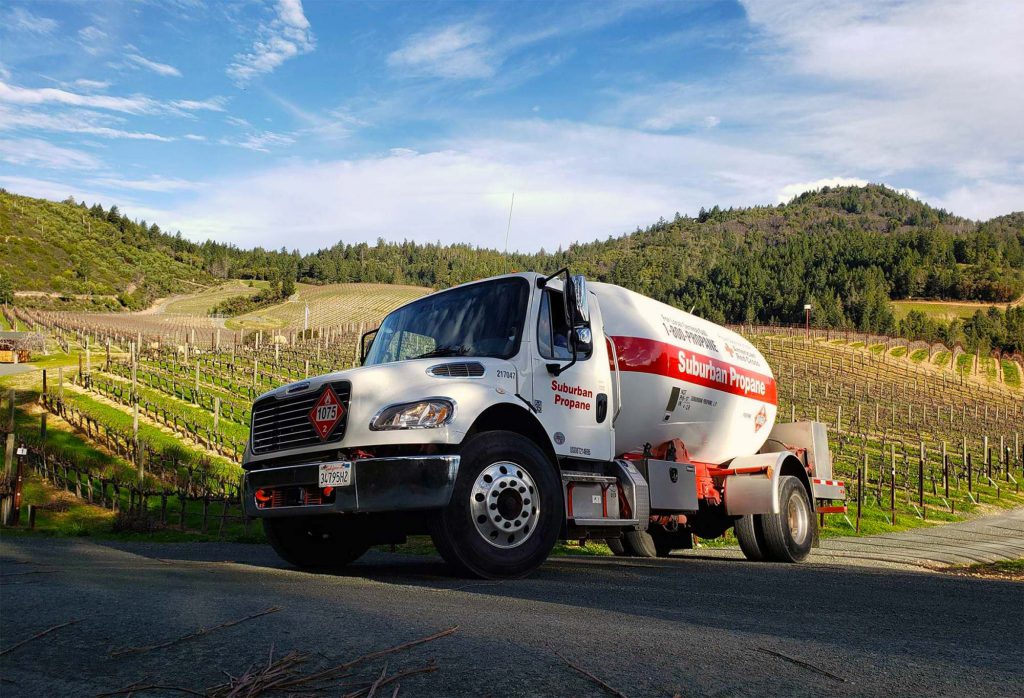 A Suburban Propane delivery truck beside rows of vines