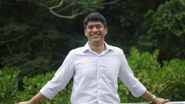 Sujay Malve standing outdoors, smiling, with trees behind him