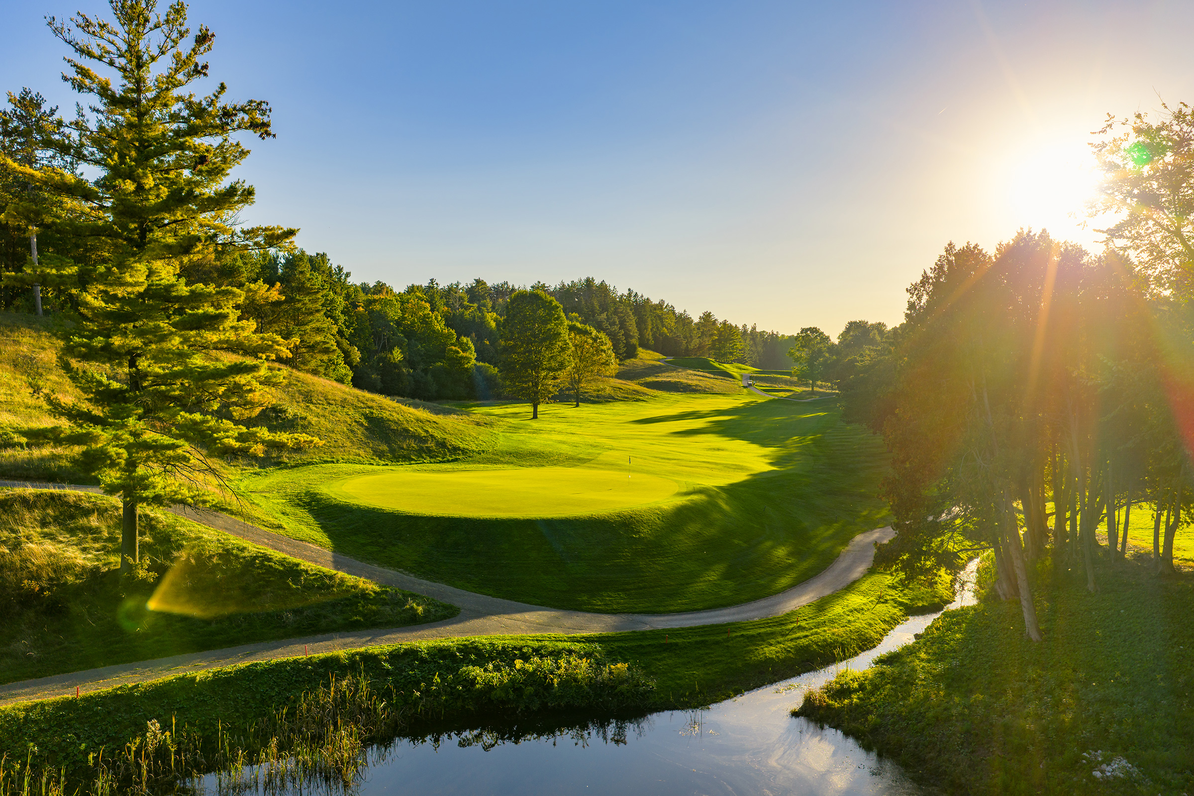 A sunlit green and rolling fairway at Summit Golf Club