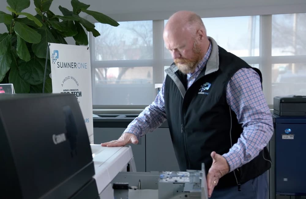 A SumnerOne specialist examining the open mechanism of a Canon production printer