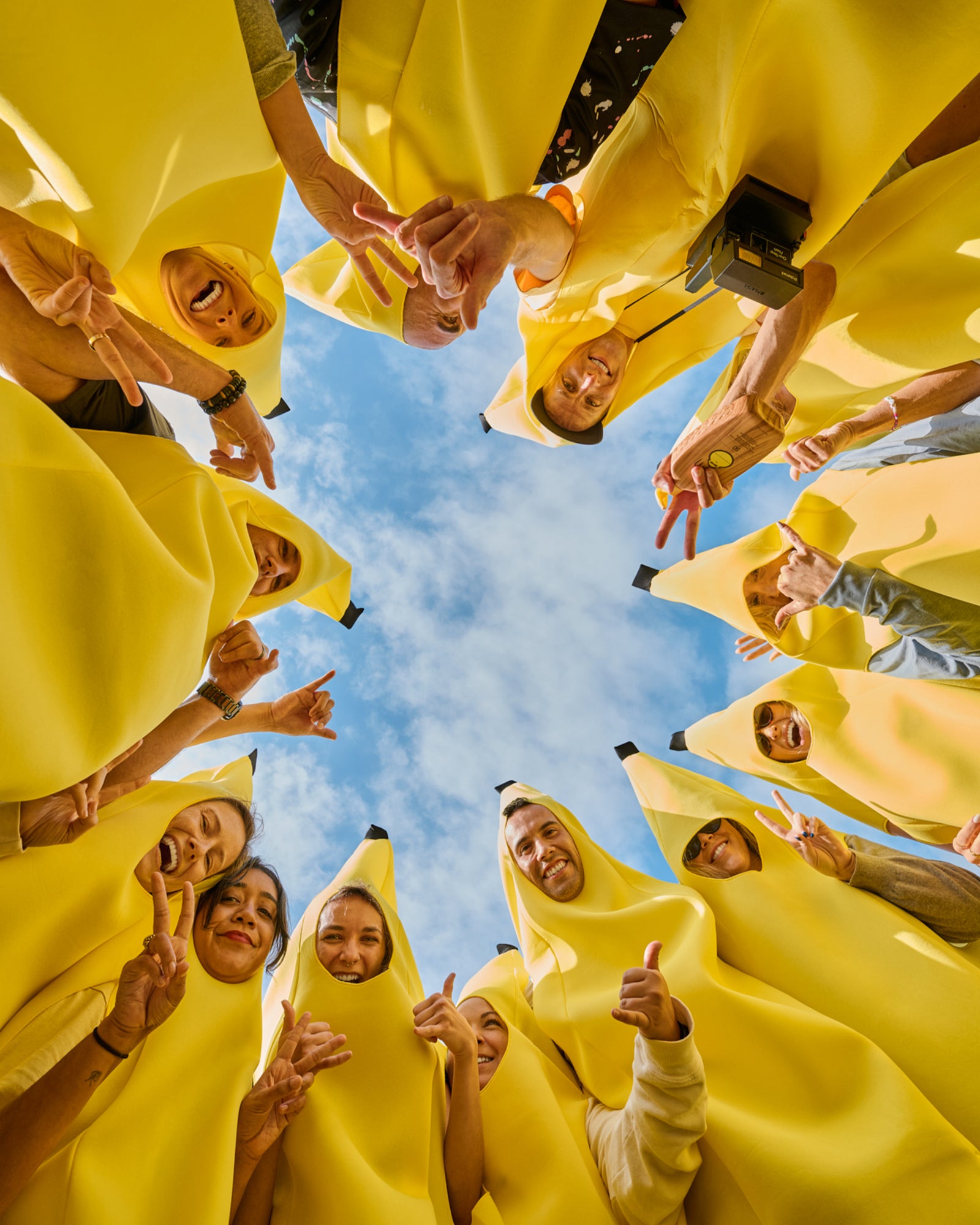 Sun Bum team members dressed in banana costumes gather beneath a blue sky