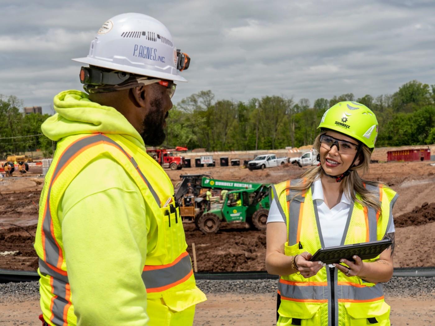 A Sunbelt representative and a construction worker talk at an active jobsite