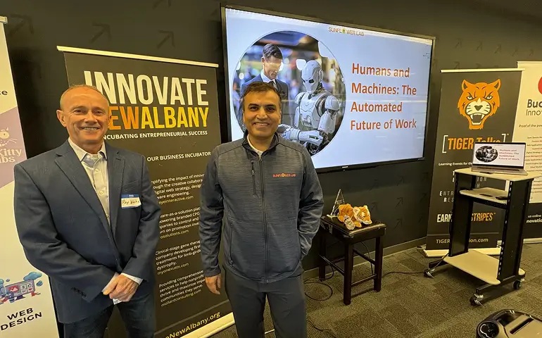 Sunflower Lab representatives at an Innovate New Albany event, beside a presentation about humans and machines